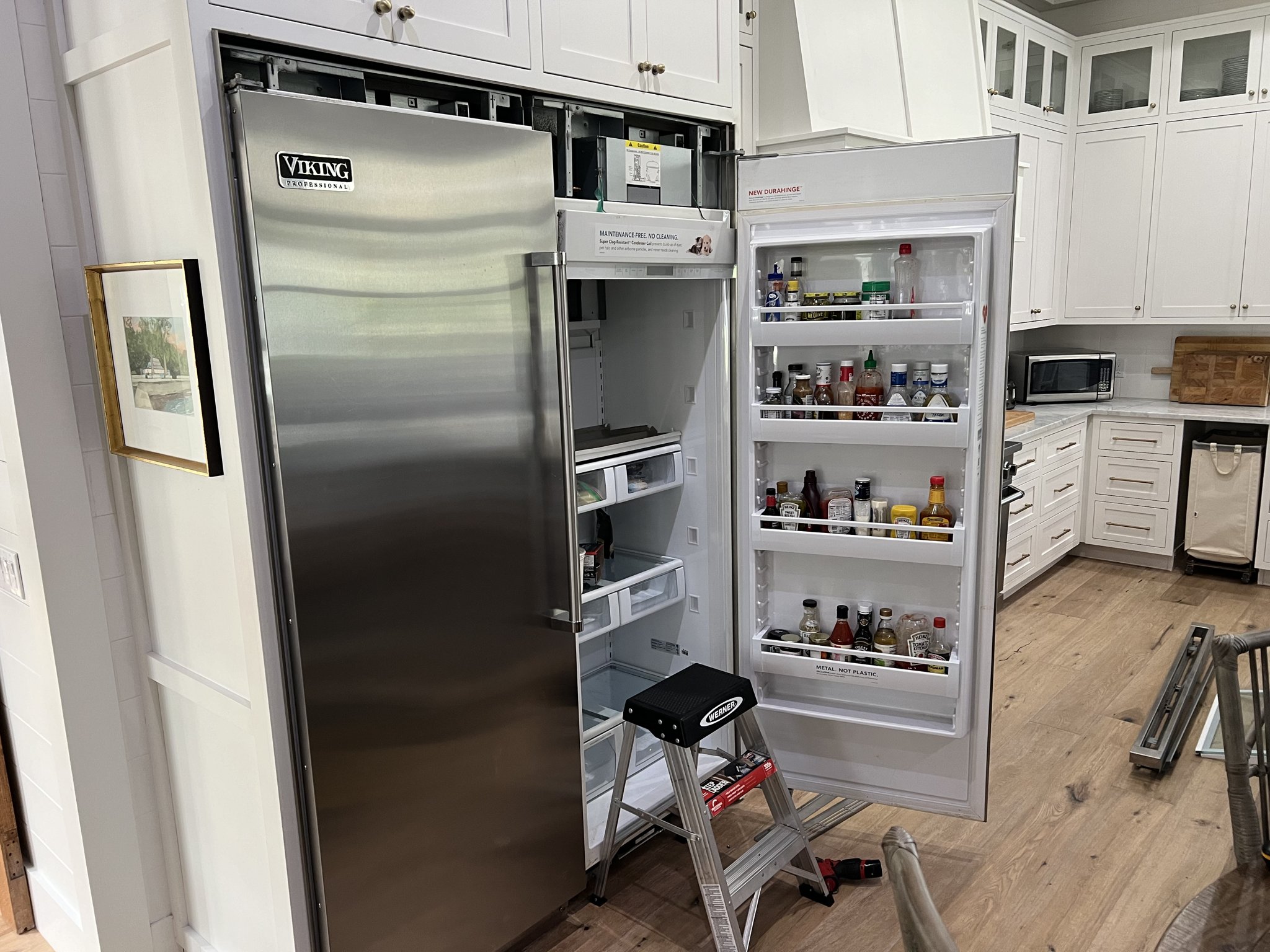 Fixer Service technician servicing an open Viking Professional built-in refrigerator in a Tampa Bay kitchen